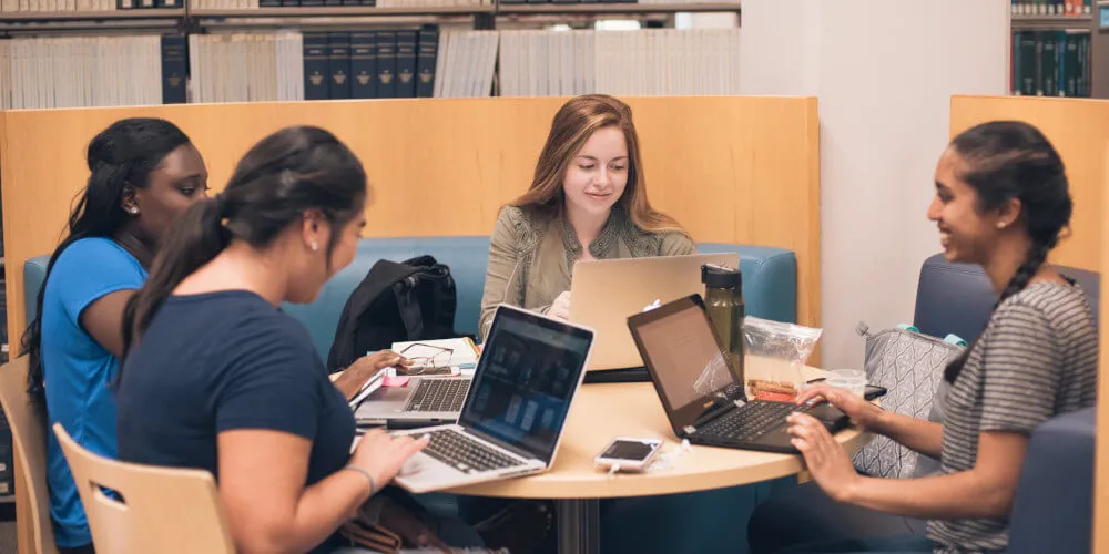 Students participating in a meeting around a small, round table.